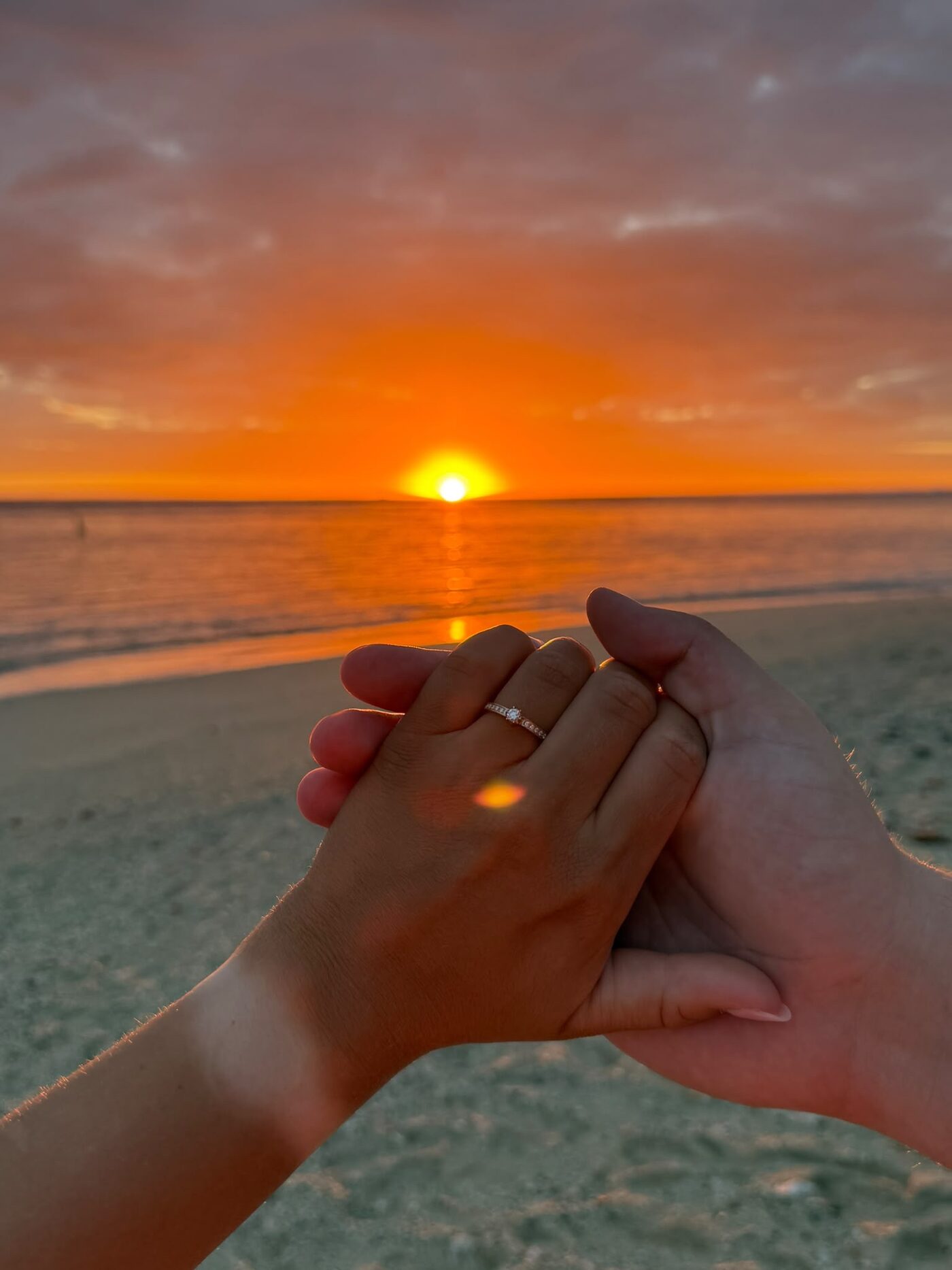 Verlobungsring an der Hand einer Frau im Licht der untergehenden Sonne
